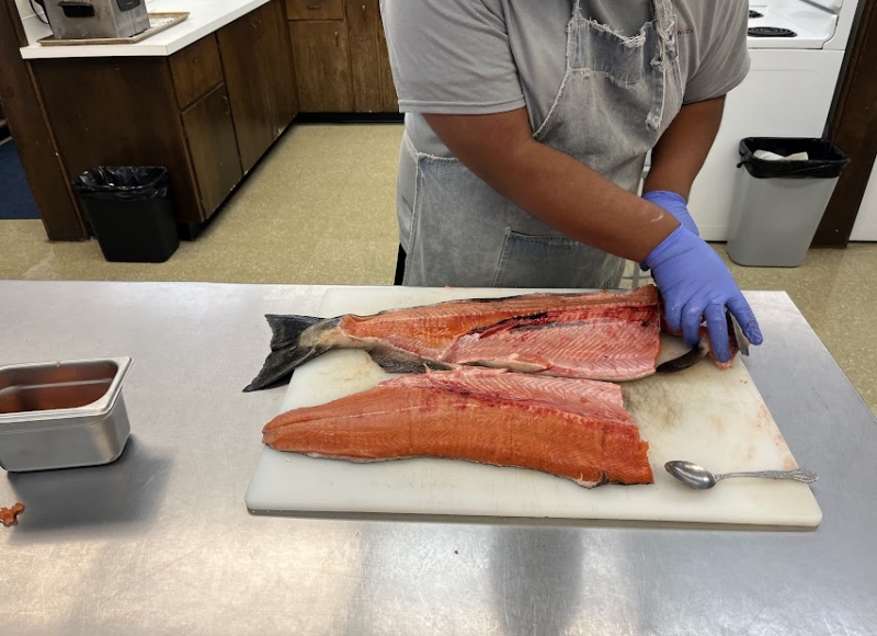 person fileting a salmon for processing.